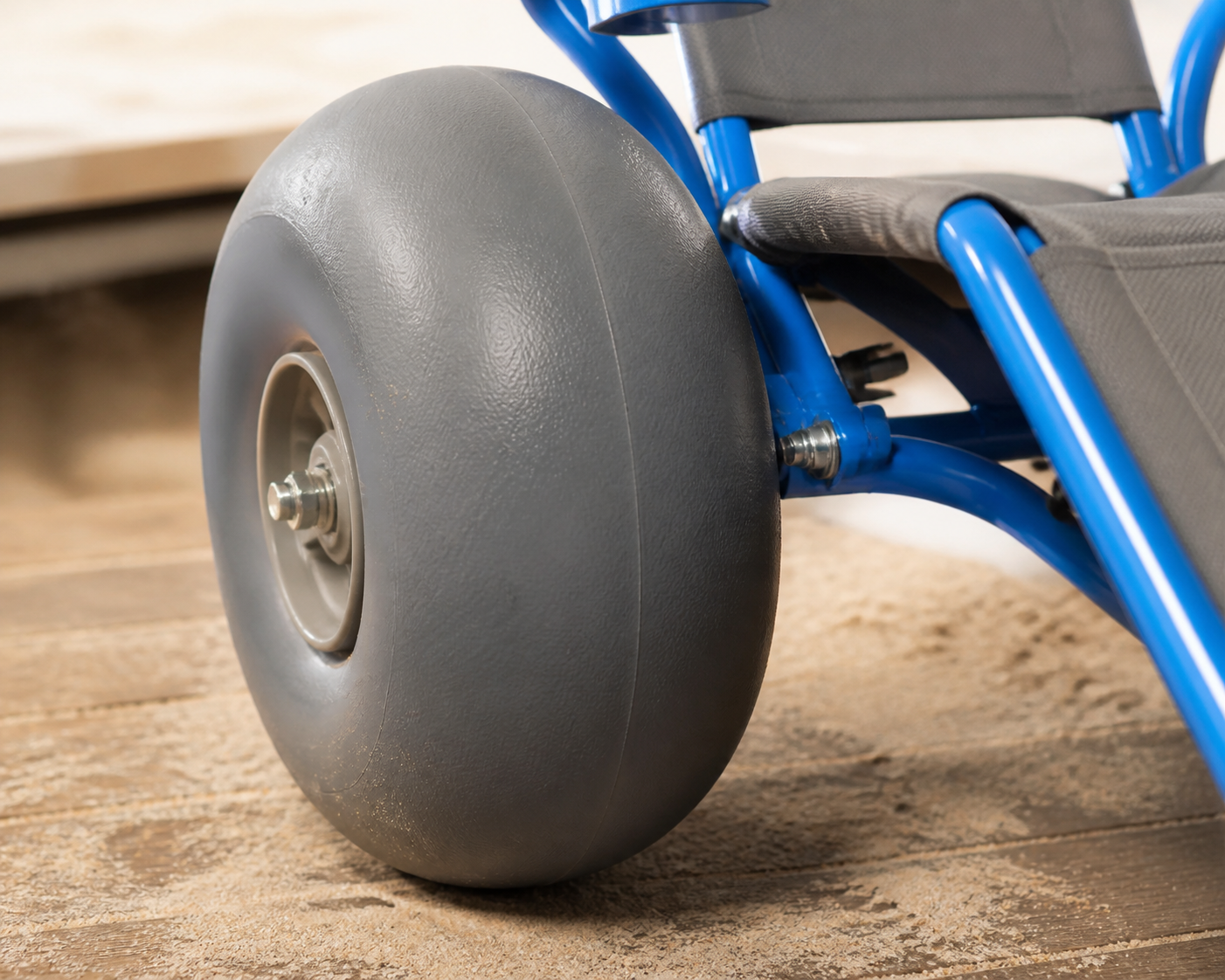Close view of an all terrain beach wheelchair balloon wheel axle and blue frame joint